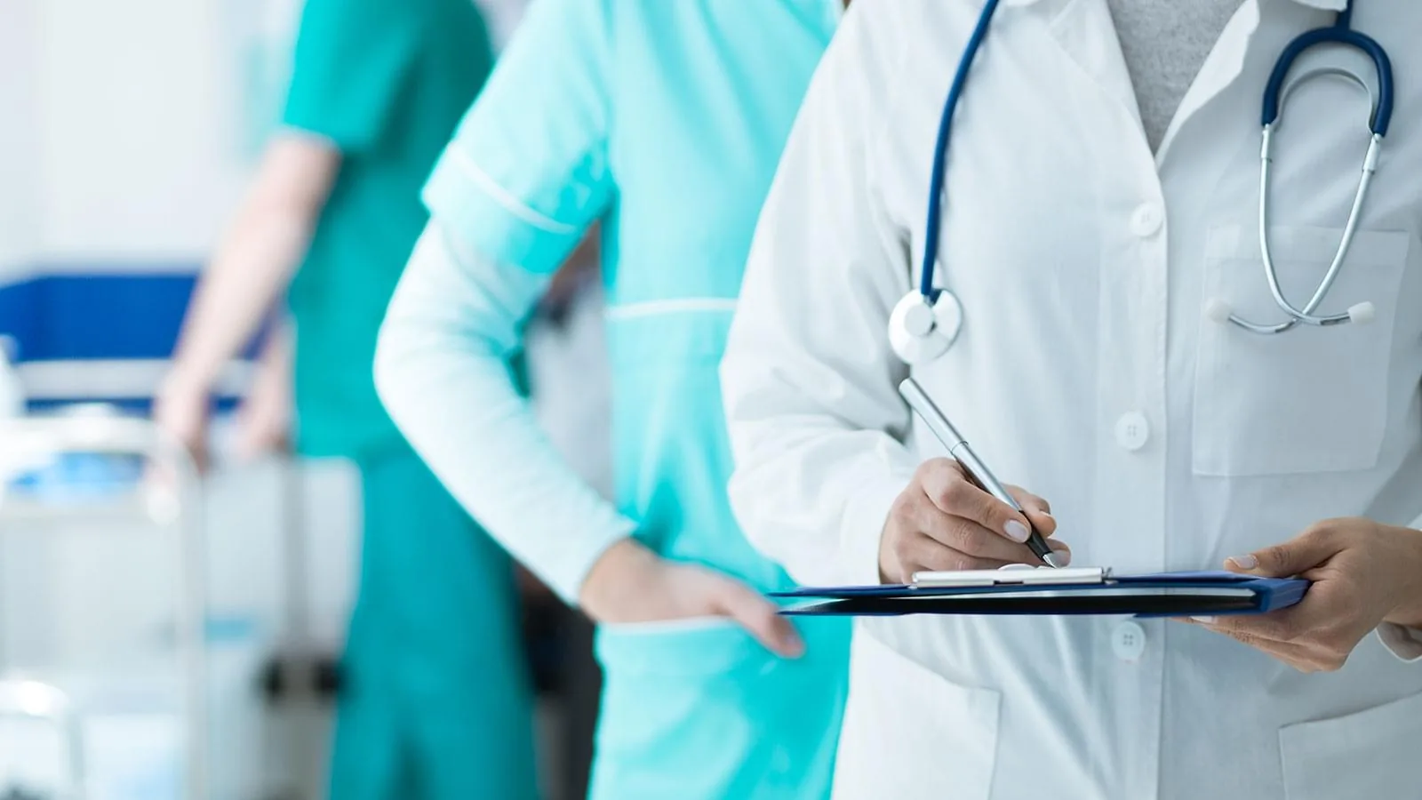 Doctor with a stethoscope holding a clipboard, with nursing staff